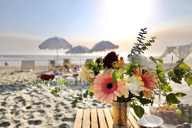 A beach table adorned with flowers and AMMSUN beach umbrellas for sand portable