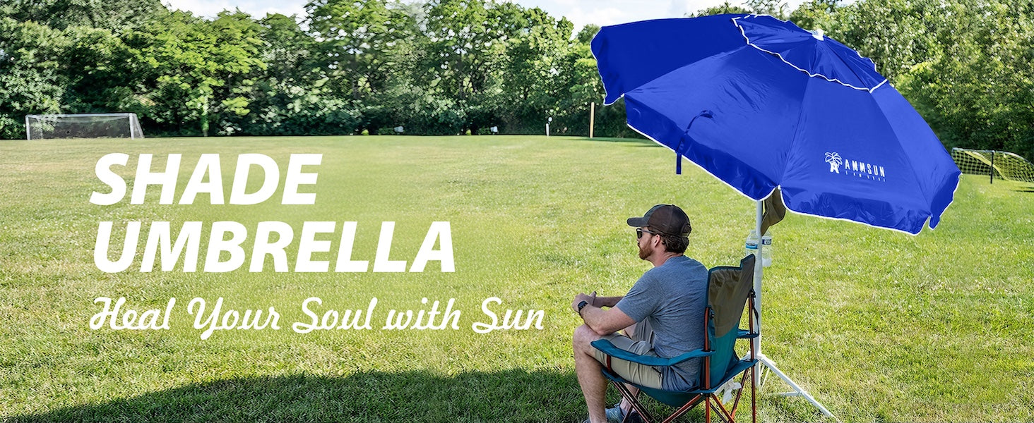A man sitting under a blue portable umbrella with stand on a grassy field