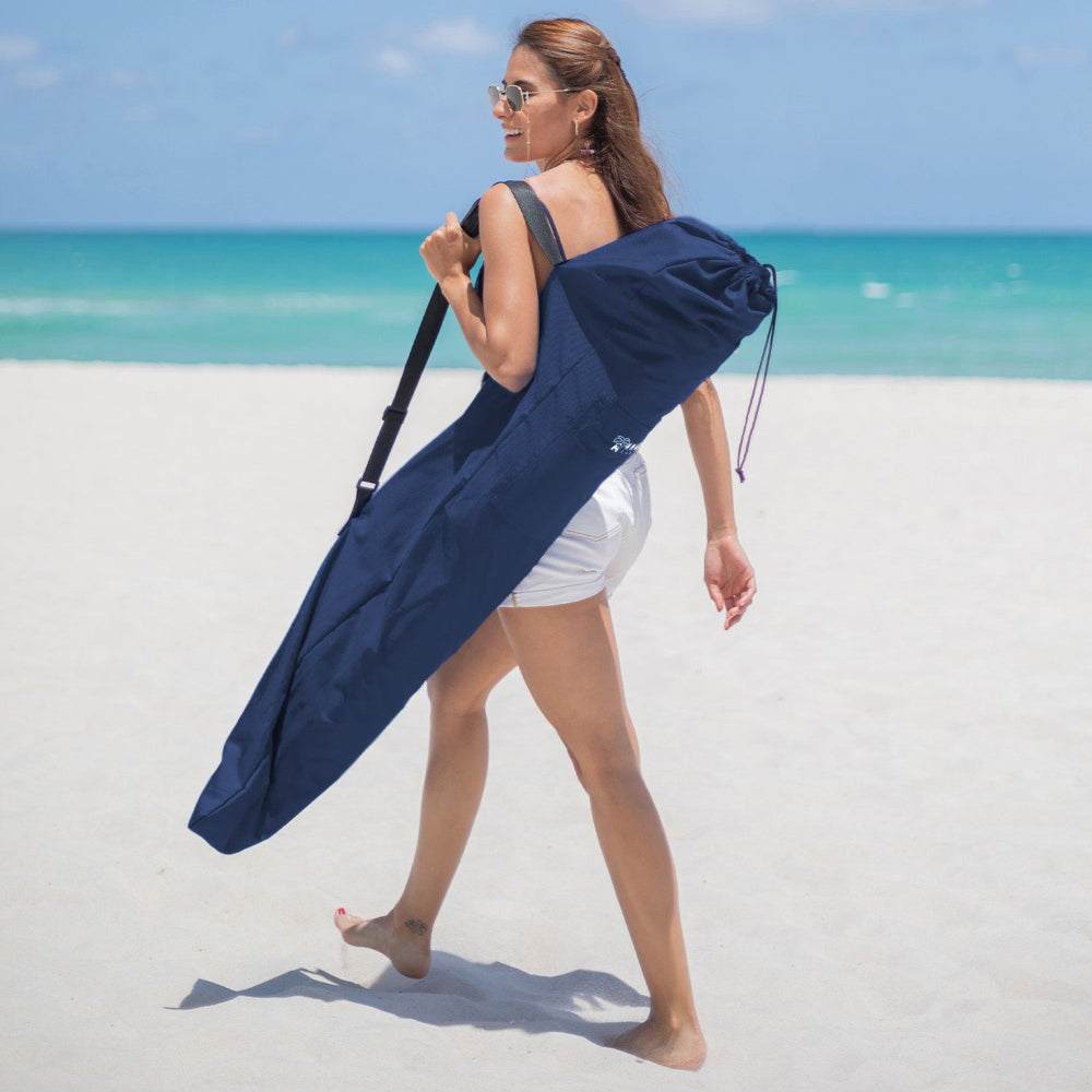 A woman is walking on the beach, carrying AMMSUN navy blue beach umbrella bags disposable