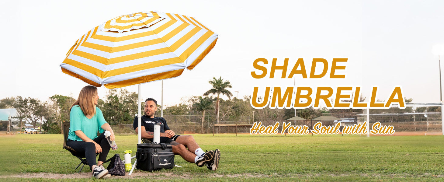 Two people sitting under an AMMSUN yellow stripes outside umbrella with outdoor umbrella stand on soccor field