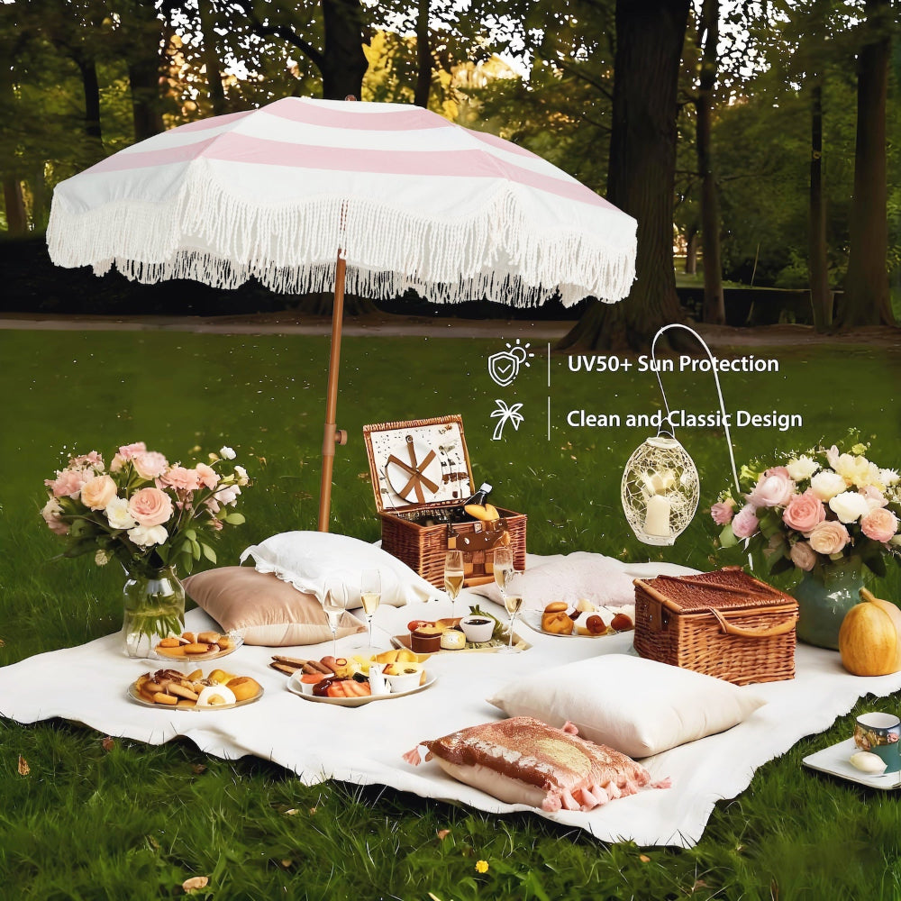 Picnic setup with an AMMSUN 6.5ft pink stripe outdoor umbrella with fringe boho umbrella, and flowers on grass