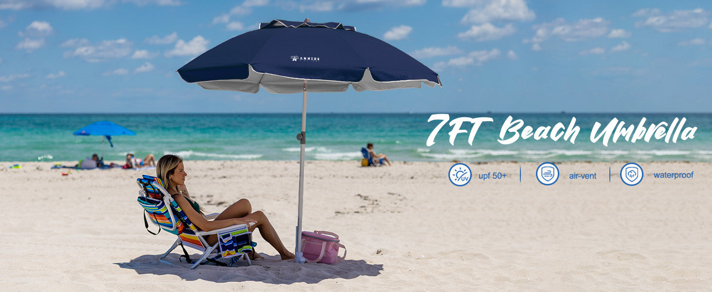 A woman sitting under an AMMSUN navy blue outdoor umbrella with beach umbrella sand anchor on a sandy beach