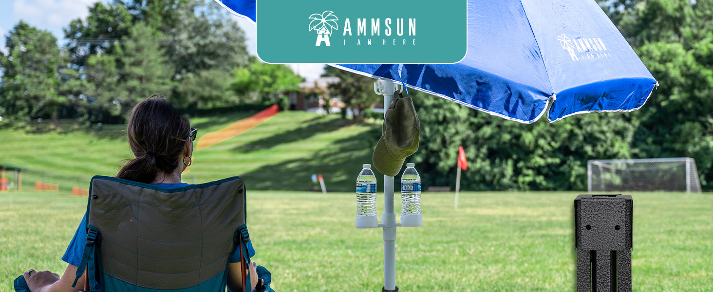 A woman sitting under a blue sports umbrella on grass with AMMSUN black patio umbrella base with additional water bag
