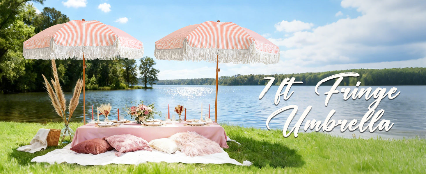 A picnic table with two AMMSUN pink patio umbrellas with tassles for outdoor umbrellas stands by a tranquil lake.