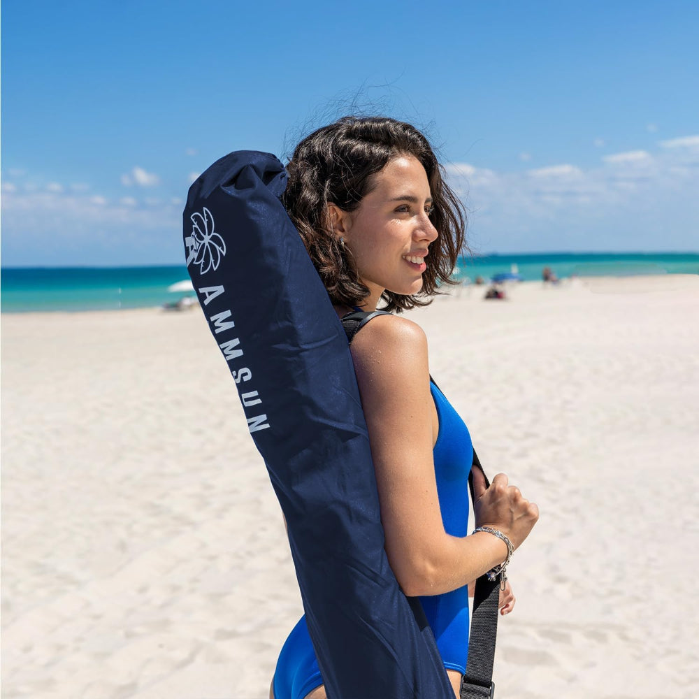 Woman holding a blue carry bag for AMMSUM beach umbrellas for sand with anchor on beach