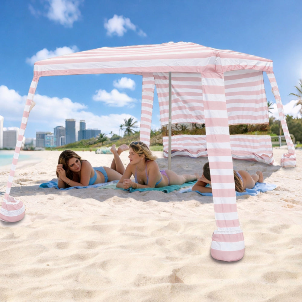 Three women lying under an AMMSUN 8'x8' pink stripes beach canopy with sand bags and side wall cabana for beach