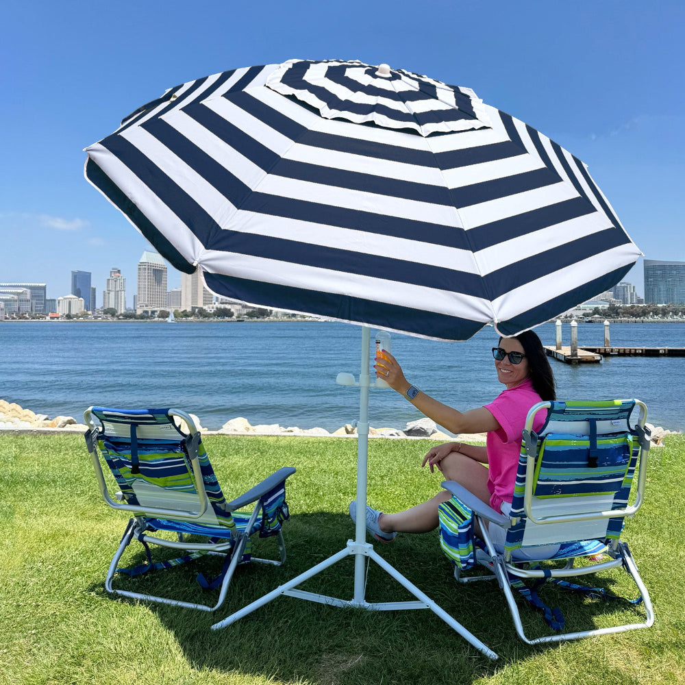 A woman sitting under a large AMMSUN 6.5ft portable umbrella with stand for outdoor sun shade