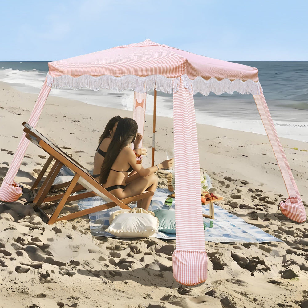 Two women sitting in the AMMSUN 7'×7' cabanas for backyard beach tent with Fringe, pink stripes canopy