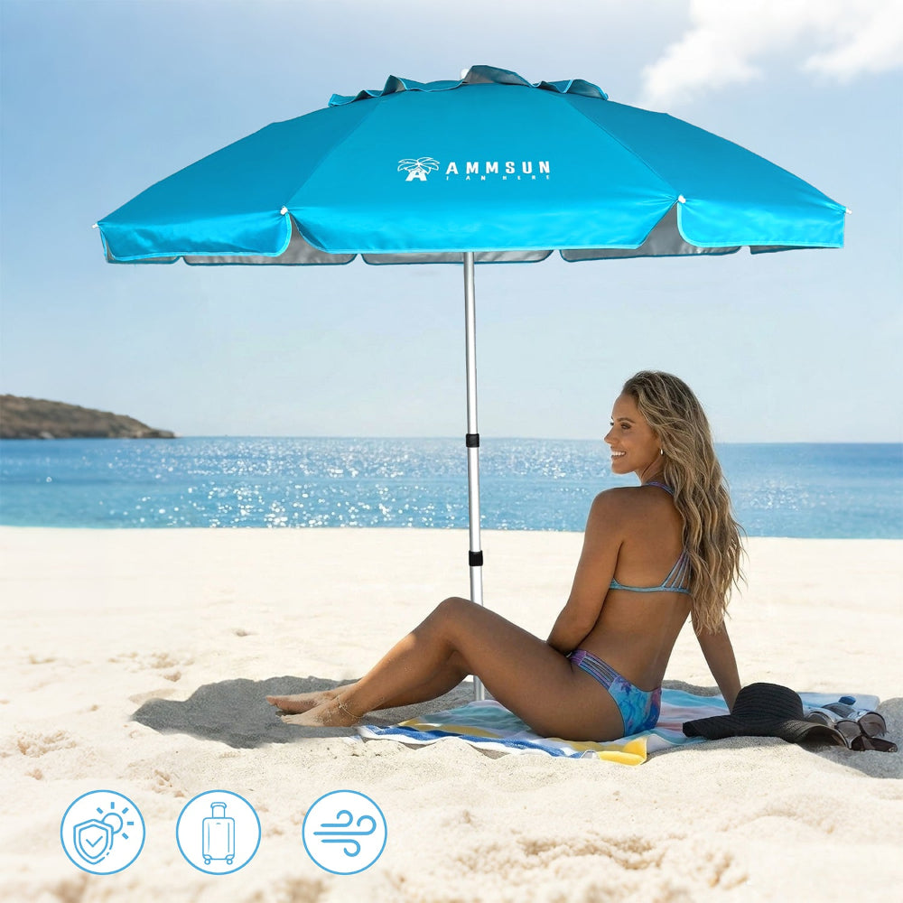 A woman in a blue bikini sits on a beach towel under an AMMSUN 6.5ft large sky blue twice folded beach umbrella on a sandy beach
