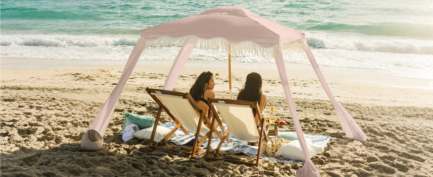 Two women sitting under an AMMSUN 7'x7' Pink Coral beach cabanas for backyard with fringe on beach