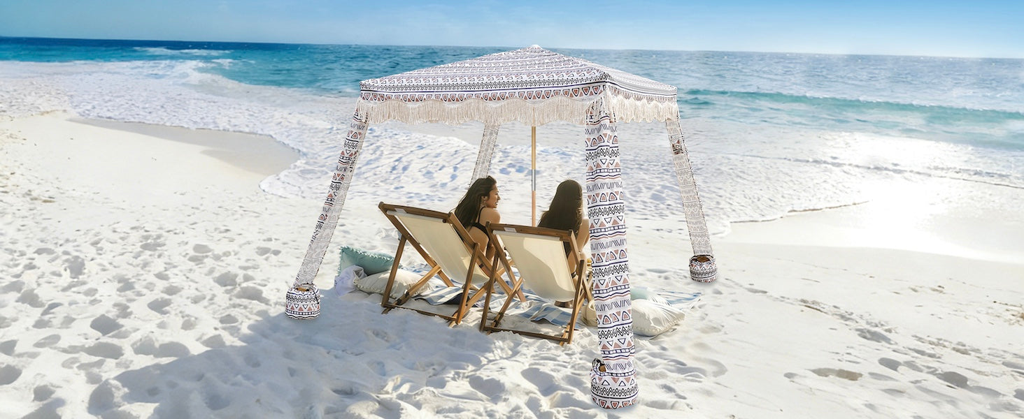 Two women sitting under an AMMSUN 7'x7' tan beach cabanas for backyard with fringe on beach