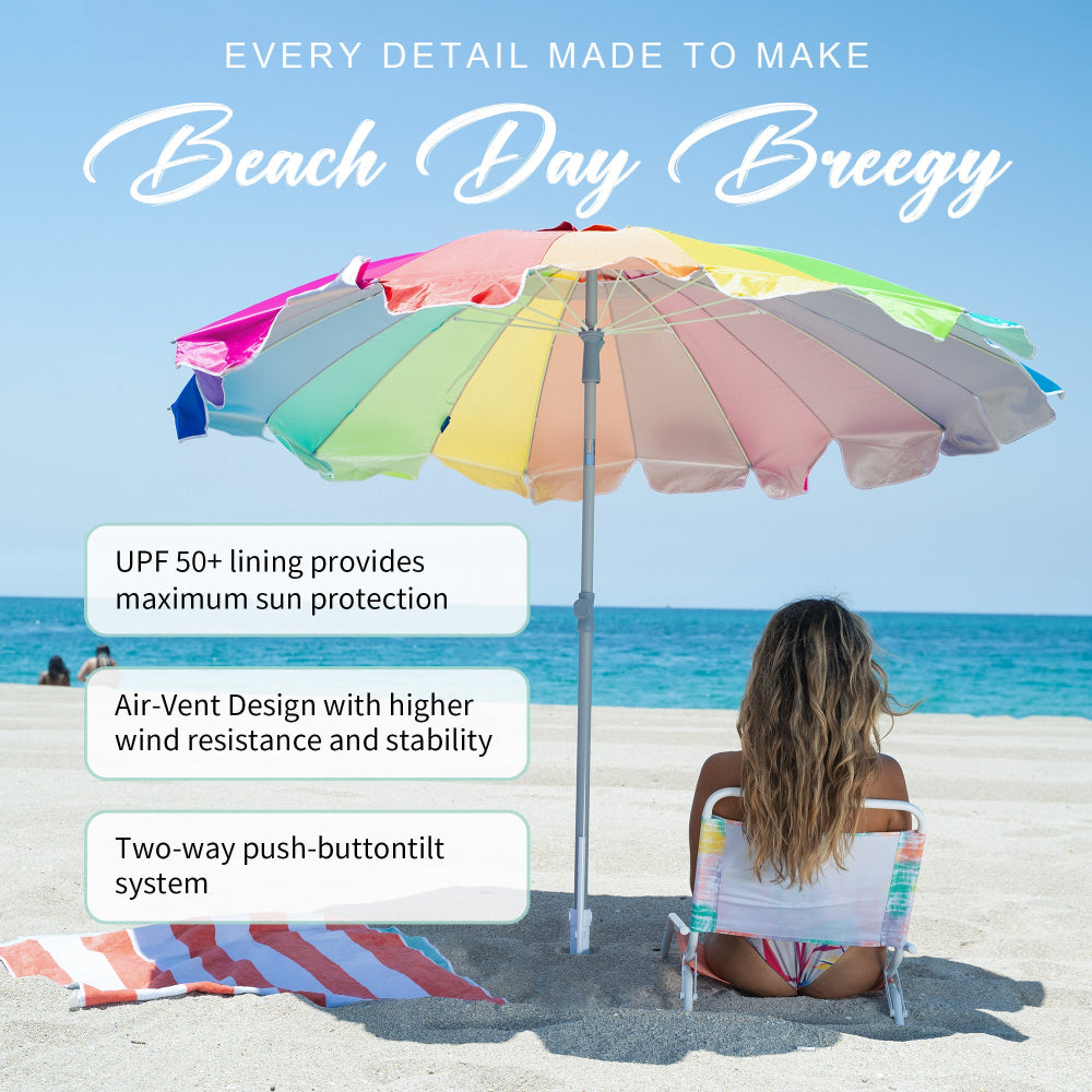 A woman is relaxing beneath AMMSUN 7.5ft rainbow travel beach umbrella with sand anchor on a sandy beach