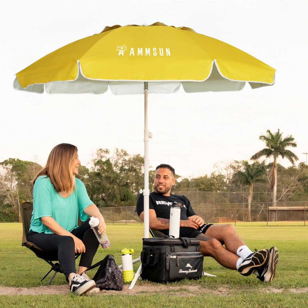 Two people sitting under AMMSUN yellow 6.5ft portable sun shades umbrella on a grassy field.