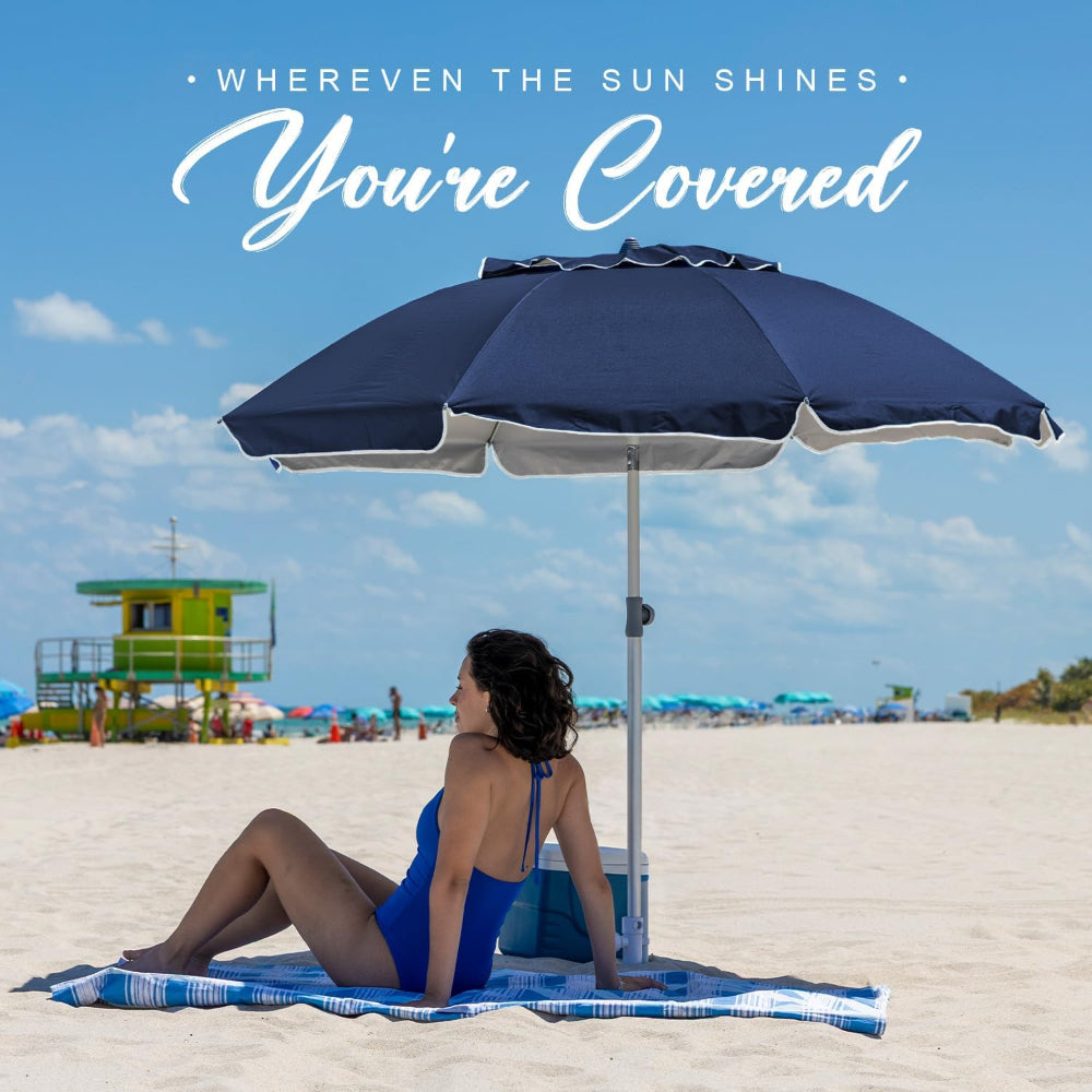 Woman sitting under a large AMMSUN 7ft blue portable beach umbrella with sand anchor on beach
