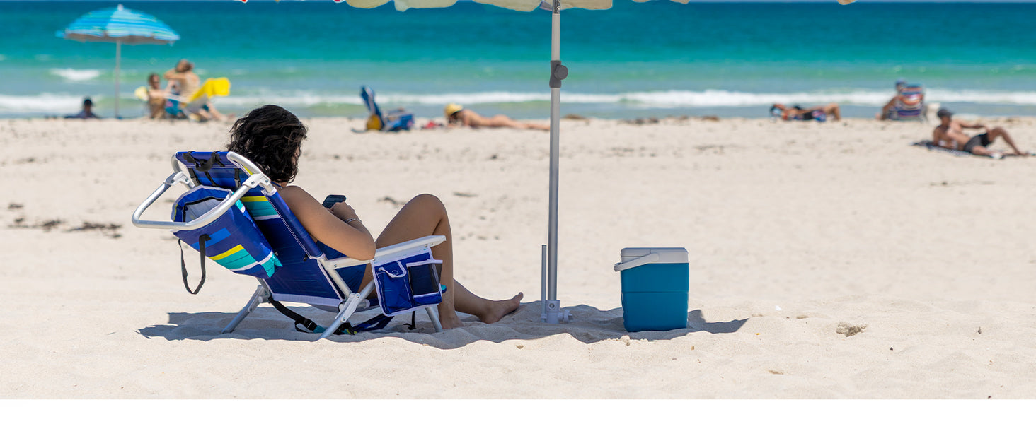A woman sitting under AMMSUN 7.5ft rainbow umbrella with beach umbrella sand anchor