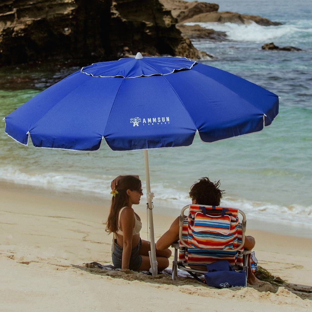 Two people sit on the beach beneath AMMSUN blue 8ft lrge size umbrella for patio with sand anchor