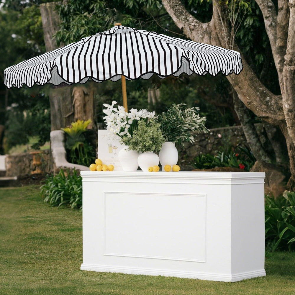 A white bar adorned with an AMMSUN  beach umbrellas for patio and vibrant flowers for outdoor setting.