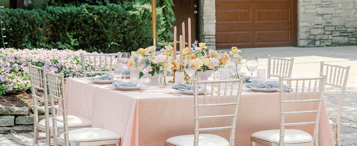 Elegant outdoor wedding setup with tables, chairs, and floral arrangements.