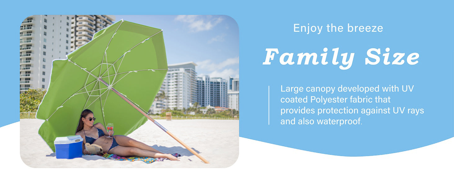 Large green heavy duty patio umbrella for beach with a person sitting under it on a sandy beach