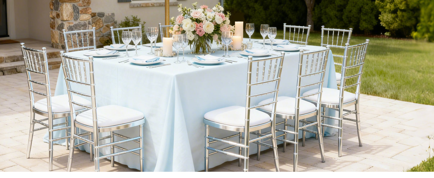 Outdoor table setting with silver chairs and a floral arrangement.