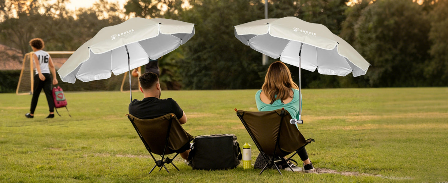 Two people sitting in chairs with beige umbrella for adults with clamp for camping chair umbrella are placed on the soccor field