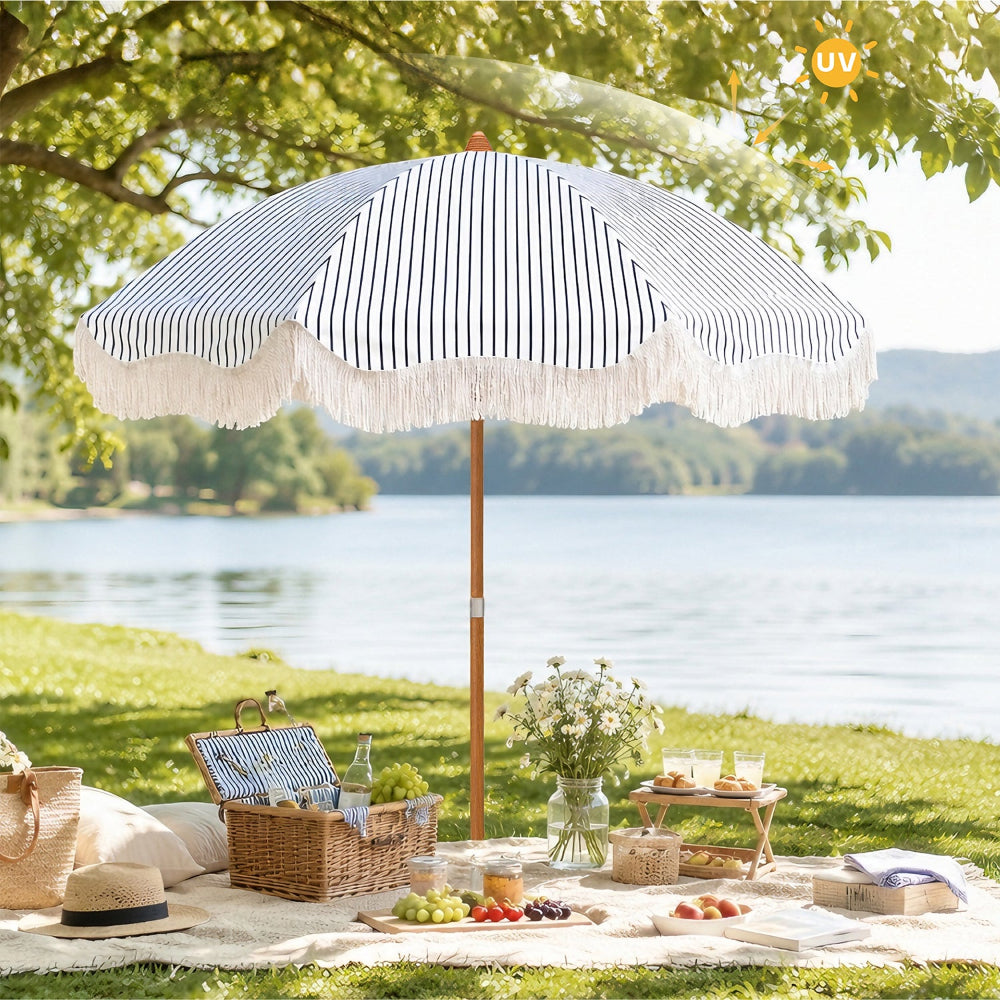 Ammsun 6.5ft neacy blue stripes fringe patio umbrellas with wood-inspired steel pole stands on a grassy lakeside lawn