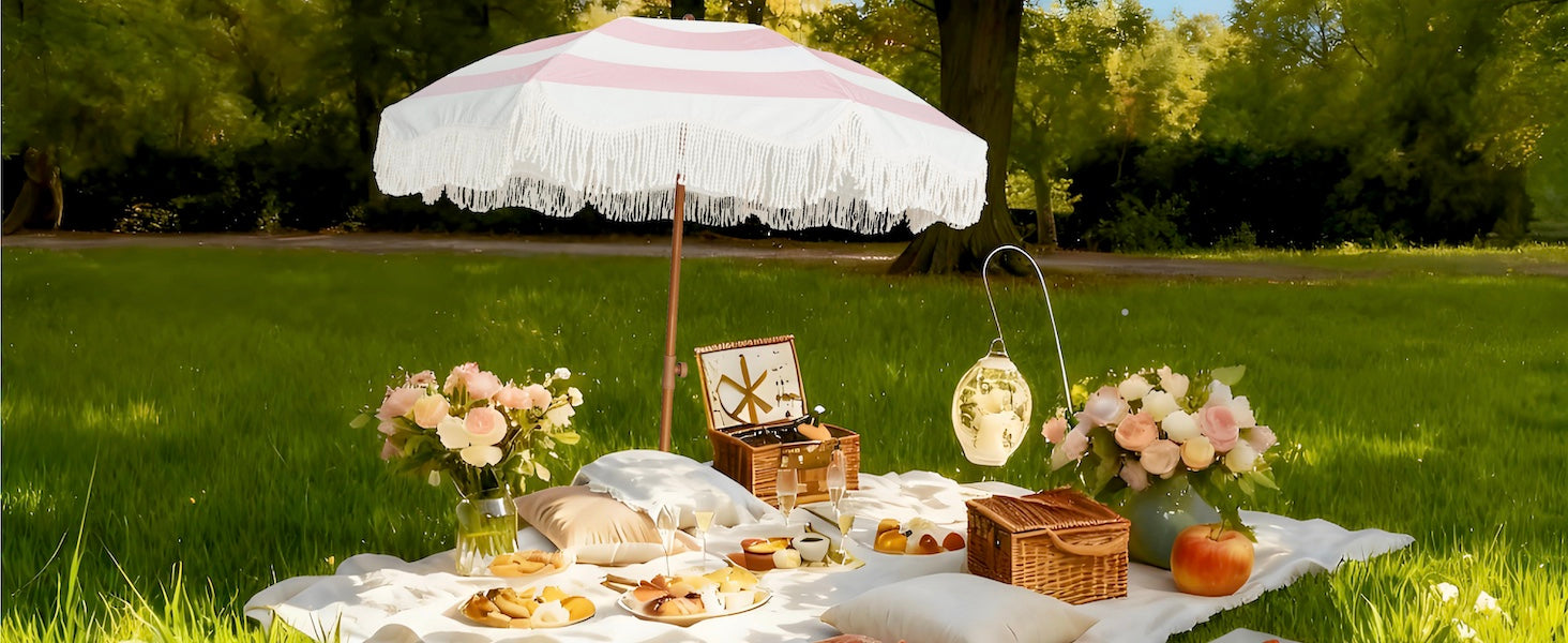 Picnic setup with AMMSUN 6.5ft pink stripe boho sunbrella patio umbrellas with tassel, food, and flowers on grass
