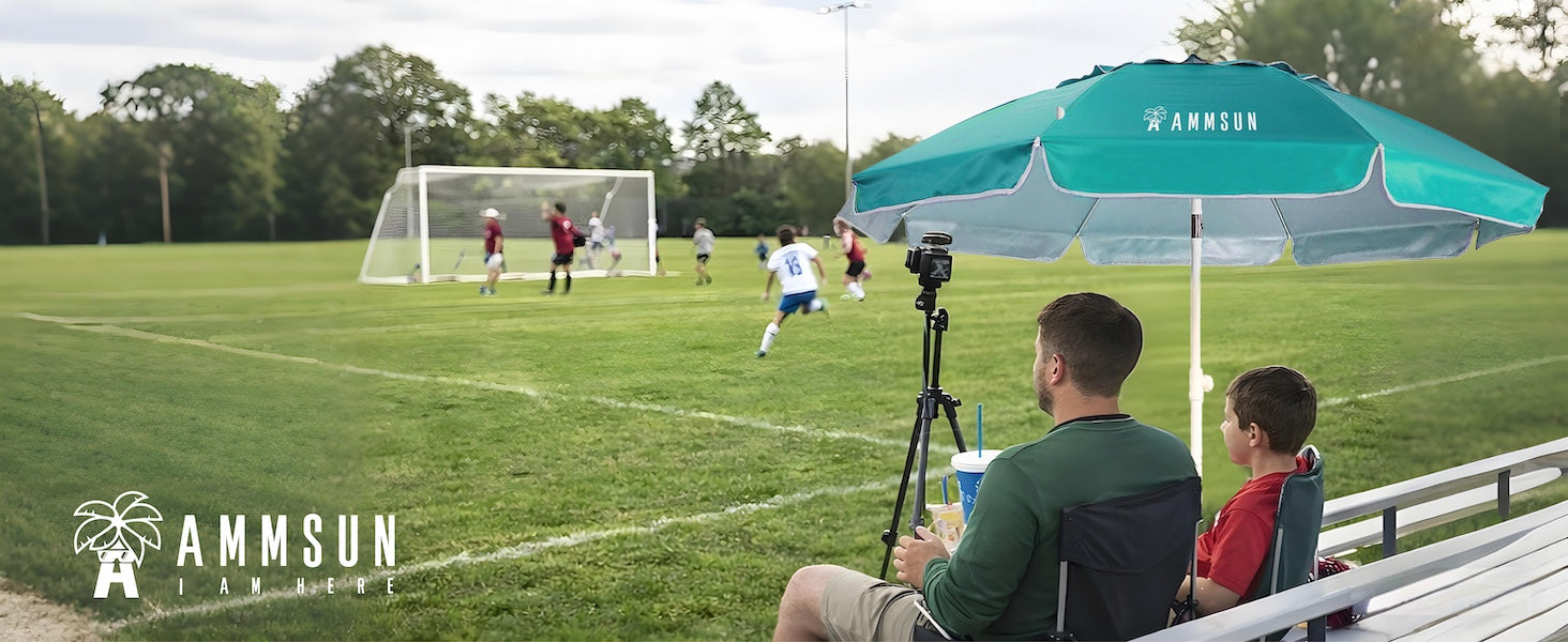 A man and boy sittng under AMMSUN 6.5ft best umbrella lightweight portable umbrella with stand for soccor game